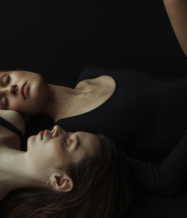 Woman performing a gentle yoga pose in a calm, dark environment.
